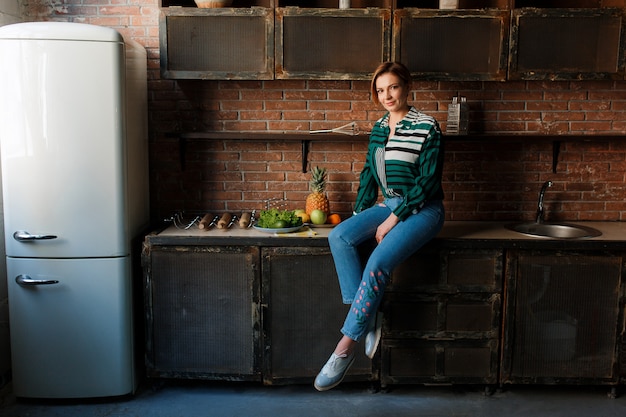 Foto grátis corte de cabelo curto da jovem mulher bonita que senta-se na mesa de cozinha.