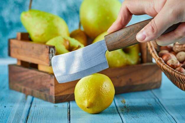 Corte de limão na mesa azul com uma cesta de madeira de maçãs.