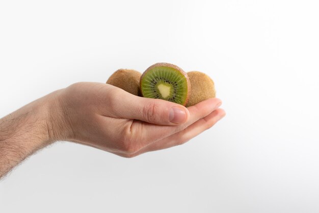 Corte e frutos de kiwi inteiros na mão humana