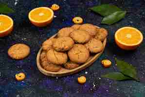 Foto grátis corte metade das laranjas e metade corte os biscoitos caseiros na placa de madeira sobre a superfície do espaço.