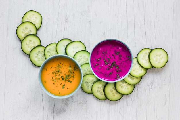 Foto grátis corte o pepino perto de tigelas com sopas