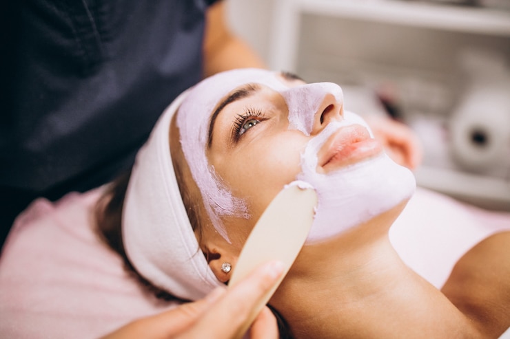 Foto grátis cosmetologista aplicando máscara no rosto de um cliente em um salão de beleza