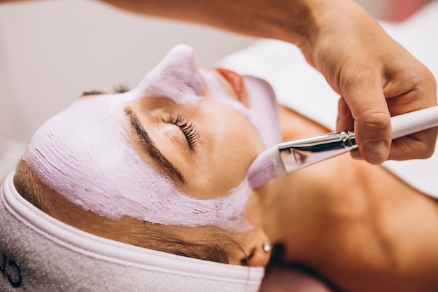 Cosmetologista aplicar máscara no rosto do cliente em um salão de beleza