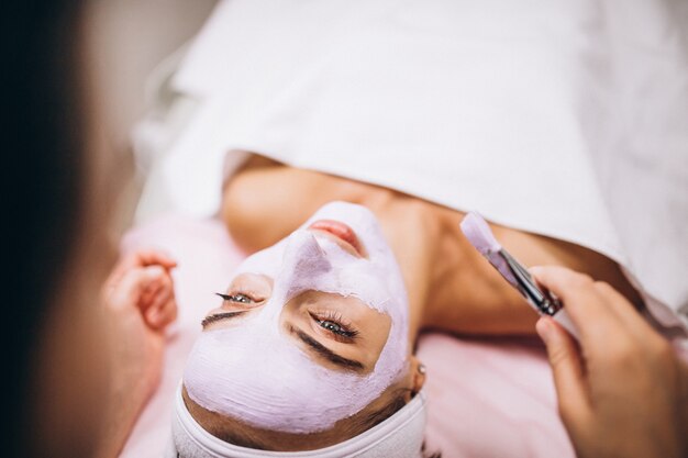 Cosmetologista aplicar máscara no rosto do cliente em um salão de beleza