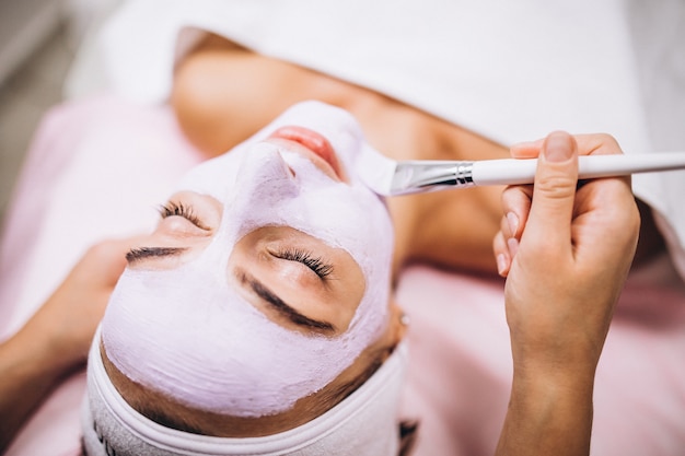 Cosmetologista aplicar máscara no rosto do cliente em um salão de beleza