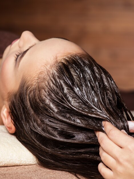 Cosmetologista massageando o cabelo da cabeça da mulher. Tratamento de spa. Tratamento de beleza. Salão spa