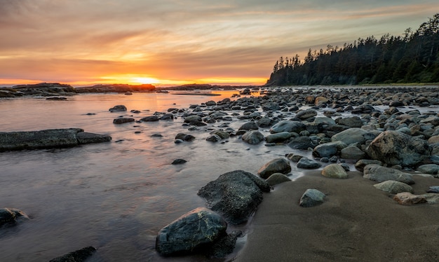 Foto grátis costa rochosa com pedras na costa durante o pôr do sol