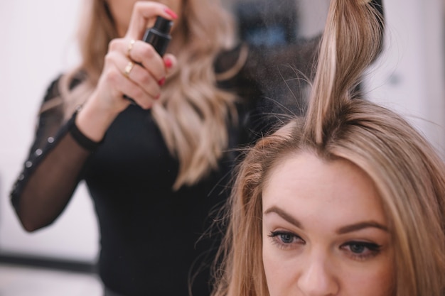Costureira de cabeleireiro aplicando spray no cabelo