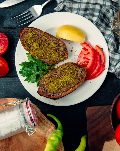 Cotlet de carne recheado cortado metade servido com limão e tomate