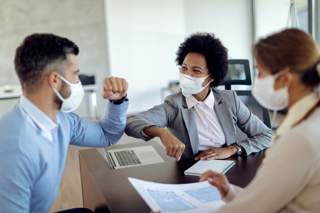 Cotovelo de agente imobiliário preto feliz batendo com seu cliente durante a reunião