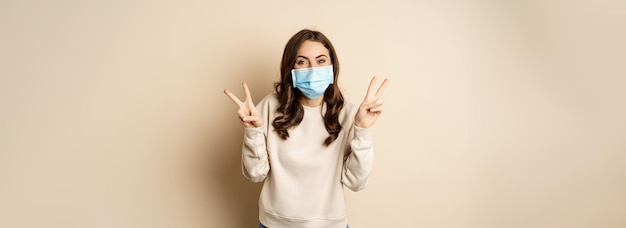 Covid pandemia e conceito de quarentena linda mulher adulta em máscara médica facial mostrando sinal de paz
