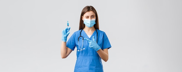 Covid19, prevenindo vírus, profissionais de saúde e conceito de quarentena enfermeira ou médica bonita em azul esfrega máscara médica ppe seringa apontando cheia de vacina contra coronavírus