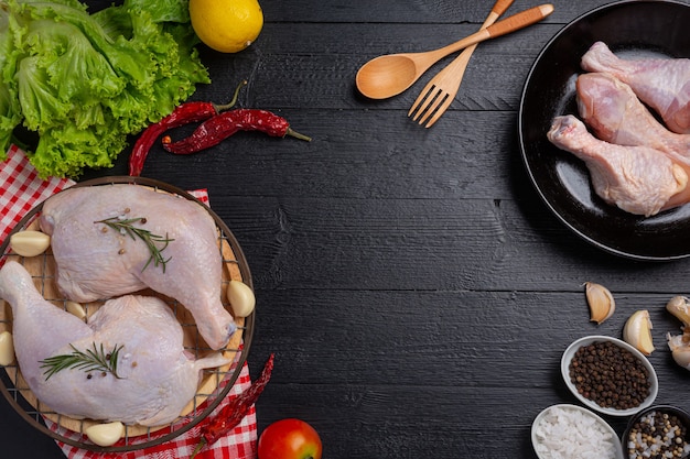 Coxas de frango cru na superfície de madeira escura.