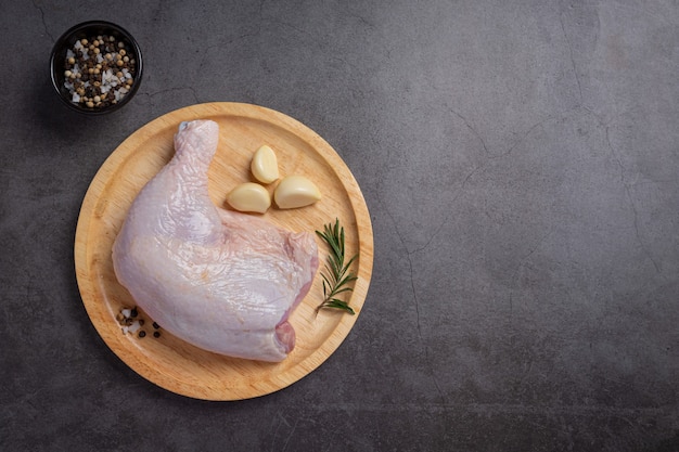 Coxas de frango cru na superfície de madeira escura.