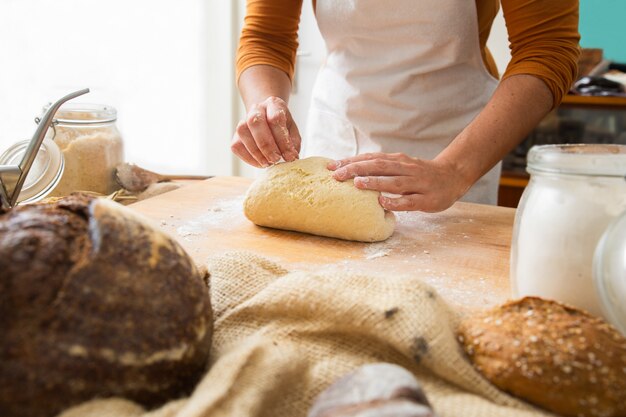 Cozinhar em pé perto da mesa e formar massa na placa de madeira