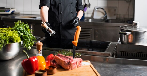 Cozinhe em pé com pimenteiro na mesa