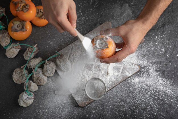 Cozinheira adiciona farinha ao doce caqui na cozinha