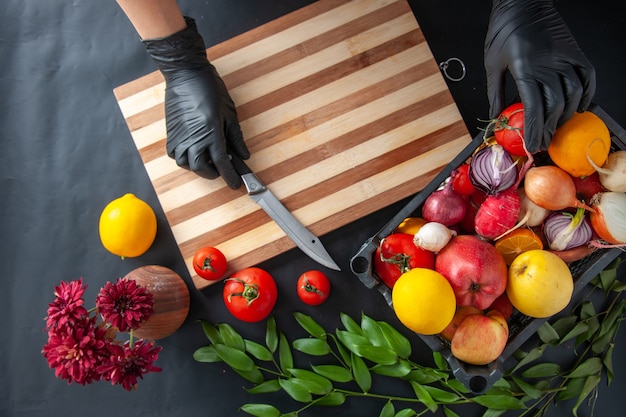 Cozinheira cortando vegetais em superfície escura