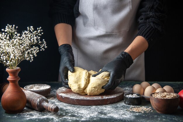 Cozinheira de frente esticando a massa em um trabalho de confeitaria escura, massa crua, torta de confeitaria