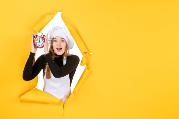 Foto grátis cozinheira de frente para a mulher segurando relógios em amarelo comida foto cor trabalho cozinha cozinha emoção tempo sol