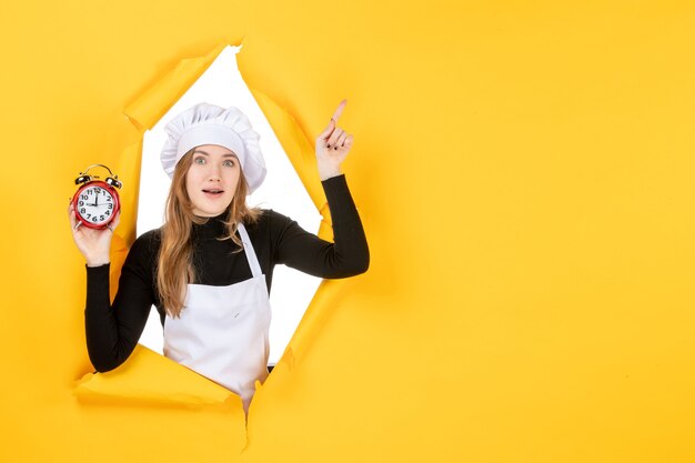 Cozinheira de frente para a mulher segurando relógios em amarelo tempo comida foto trabalho cozinha emoção sol cozinha cor