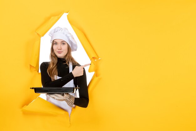 Cozinheira de frente para a mulher segurando uma panela preta com biscoitos no amarelo emoção sol comida trabalho cozinha cozinha cor