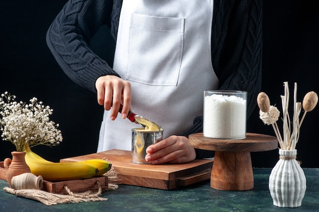 Cozinheira de frente tentando abrir uma lata com leite condensado em fundo escuro