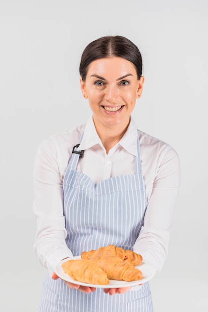 Foto grátis cozinheiro chefe de pastelaria feminino segurando placa com croissant