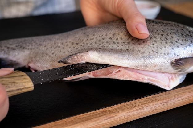 Foto grátis cozinheiro de alto ângulo limpando peixe na cozinha