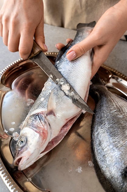 Cozinheiro de alto ângulo limpando peixe na cozinha