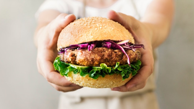 Cozinheiro de close-up, segurando o hamburguer nas mãos