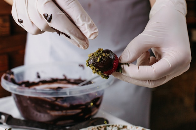 Foto grátis cozinheiro de morango choco mergulhando morango vermelho dentro de chocolate