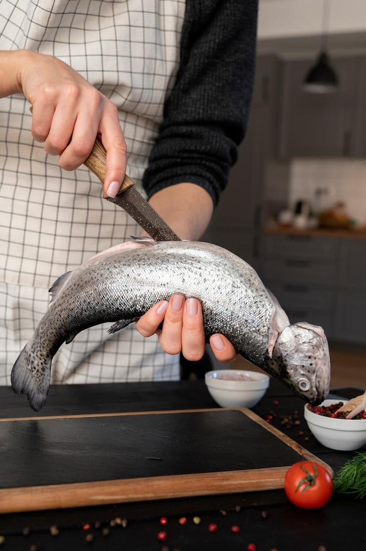 Foto grátis cozinheiro de vista frontal limpando peixe na cozinha