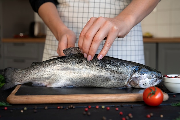 Foto grátis cozinheiro de vista frontal limpando peixe na cozinha