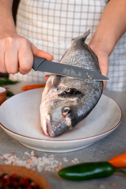 Foto grátis cozinheiro de vista frontal limpando peixe na cozinha