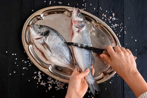 Foto grátis cozinheiro de vista superior limpando peixe na cozinha