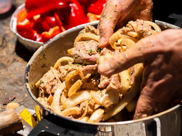 Cozinheiro irreconhecível, misturando pedaços de carne e cebola para shashlik