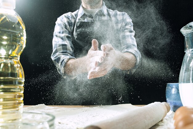 Cozinheiro profissional polvilha a massa com farinha