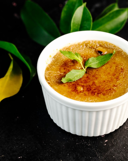 Creme brule em tigela branca com folhas de hortelã.