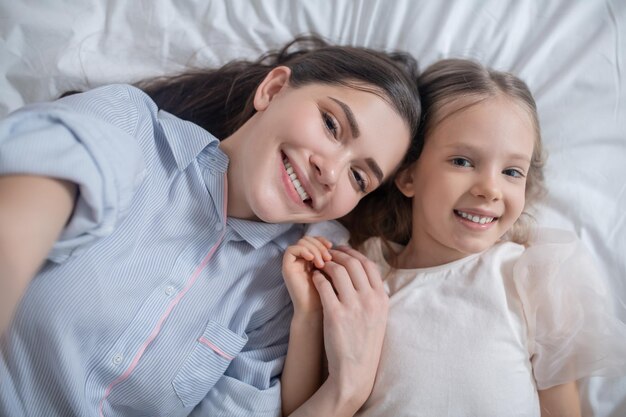 Criança alegre e sua mãe atraente posando para a câmera