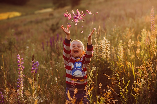 Criança alegre lança pétalas levantando-se no campo de lavander