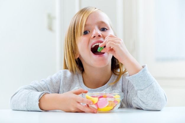 Criança bonita comendo doces em casa.