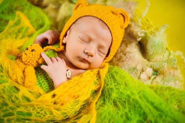 Criança bonita dorme sob lenço verde na cesta