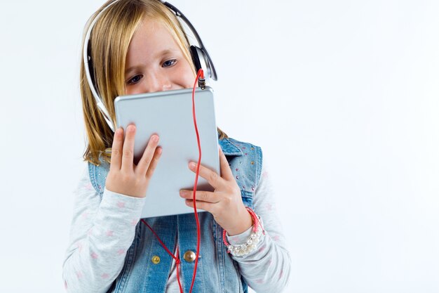 Criança bonita que escuta a música com tabuleta digital.