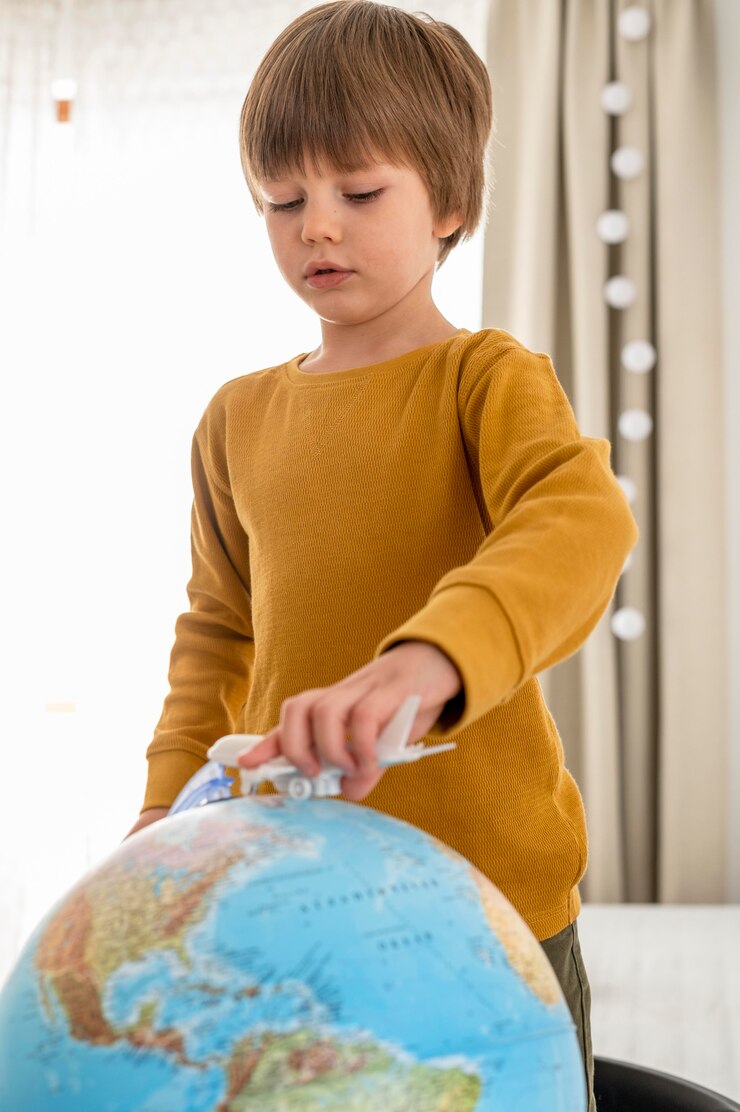 Foto grátis criança brincando com estatueta de avião e globo