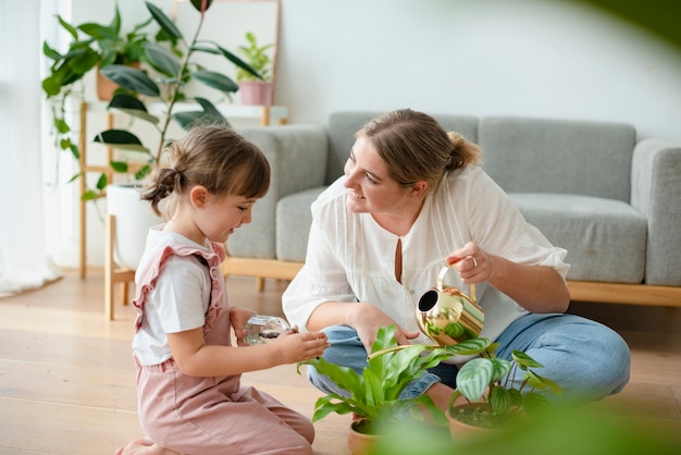 Foto grátis criança com mãe regando vasos de plantas em casa