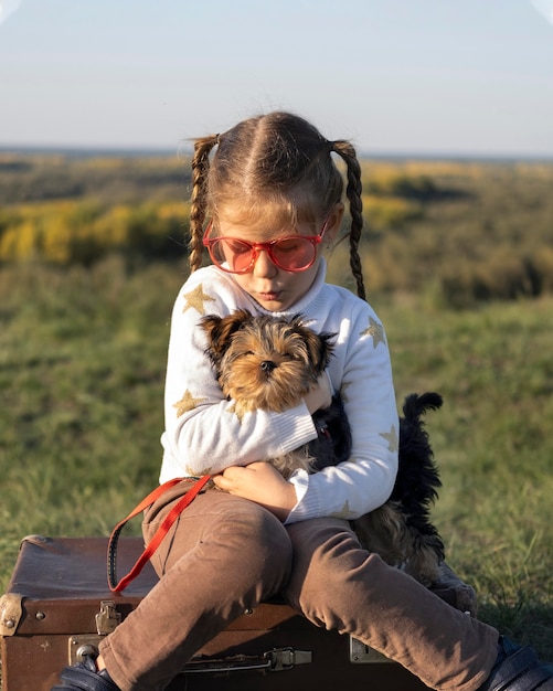 Criança com óculos escuros brincando com a vista frontal do cachorro