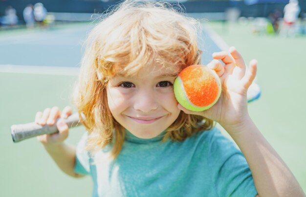 Criança com raquete de tênis e bola na quadra de tênis exercício esportivo ao ar livre para crianças atividades de verão ...