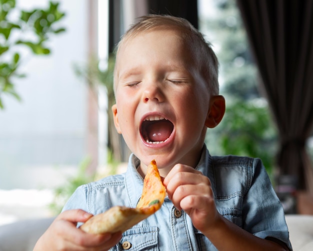 Criança com tiro médio comendo fatia de pizza