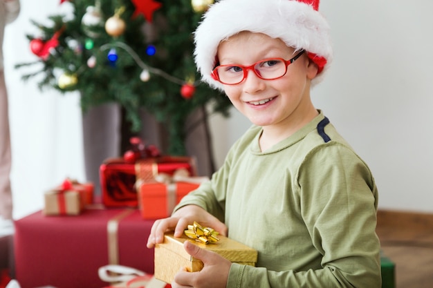 Criança com um presente dourado e um chapéu de Santa